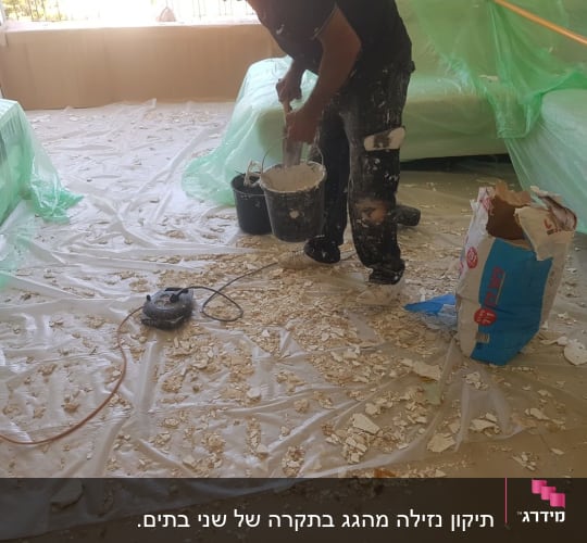 אדם מערבב טיח עם דלי וכלים על רצפה מכוסה בניילון